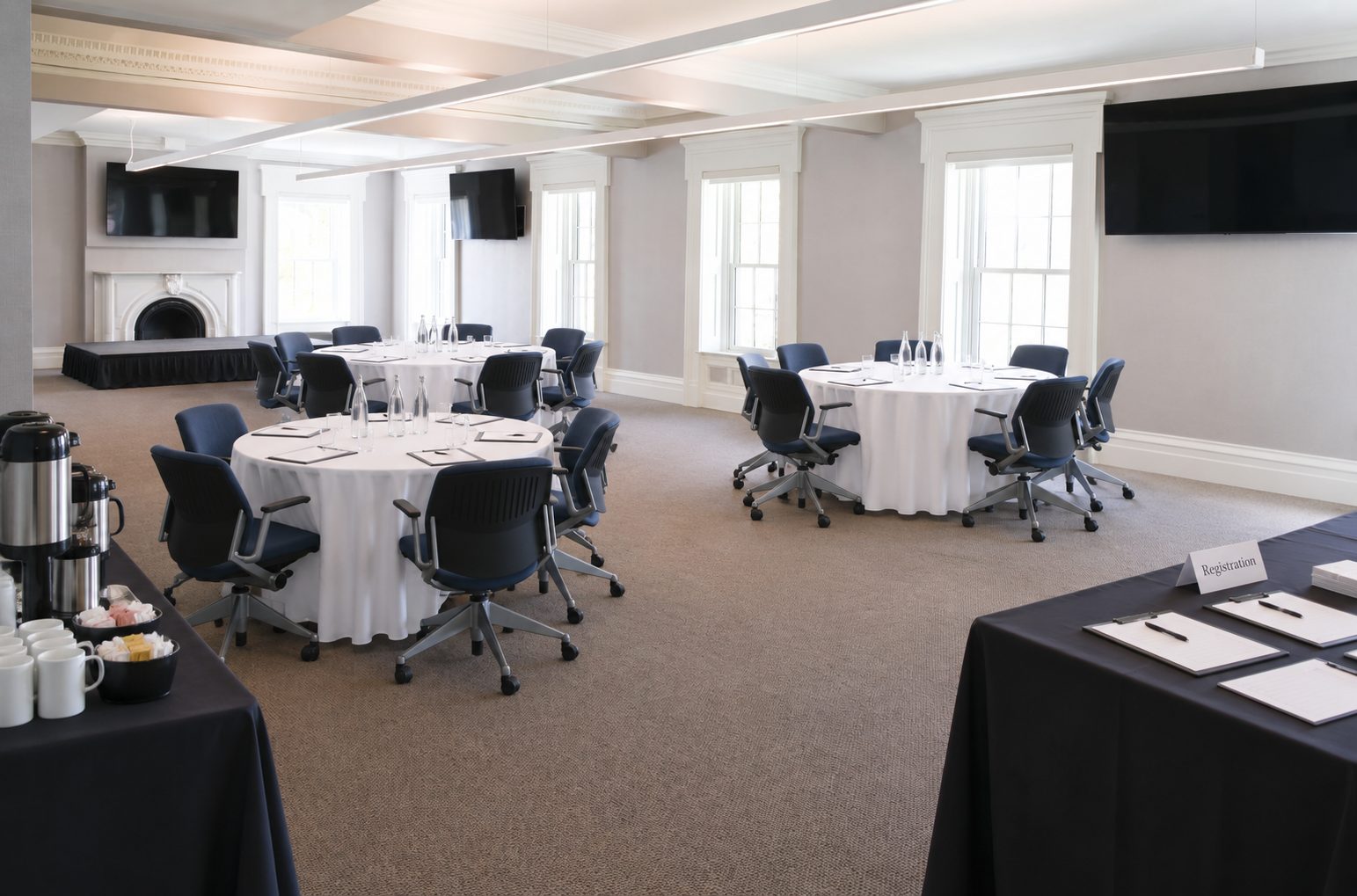 AI-edited photograph of the real meeting room with a stage, round tables, coffee station and registration table
